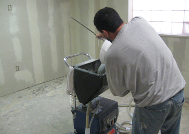 A worker fills the hopper of the texture spraying machine.