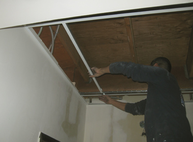 A worker installs more T-Bar to hold ceiling tiles.