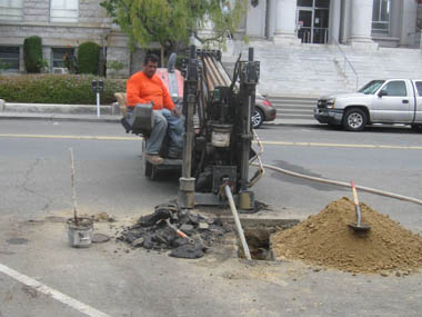 Drilling a horizontal hole under the street and sidewalk for the placement of a conduit.