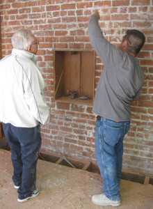 Engineer Marvin Kinney inspects a hole drilled in a brick wall.