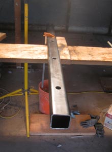 A short steel column sits on a fabrication bench.