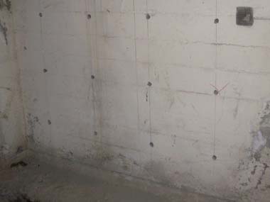 Holes drilled into the basement wall where steel rebar will be epoxied.