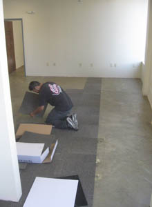 A worker lays carpet tiles.